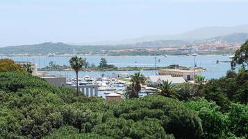 A marina with boats docked, surrounded by greenery and hills in the background.
