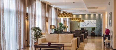 A spacious lobby with a sofa, coffee table, and potted plants.