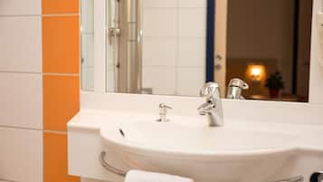 Een badkamer met een wit wastafelmeubel, een grote spiegel en oranje tegels op de muur.