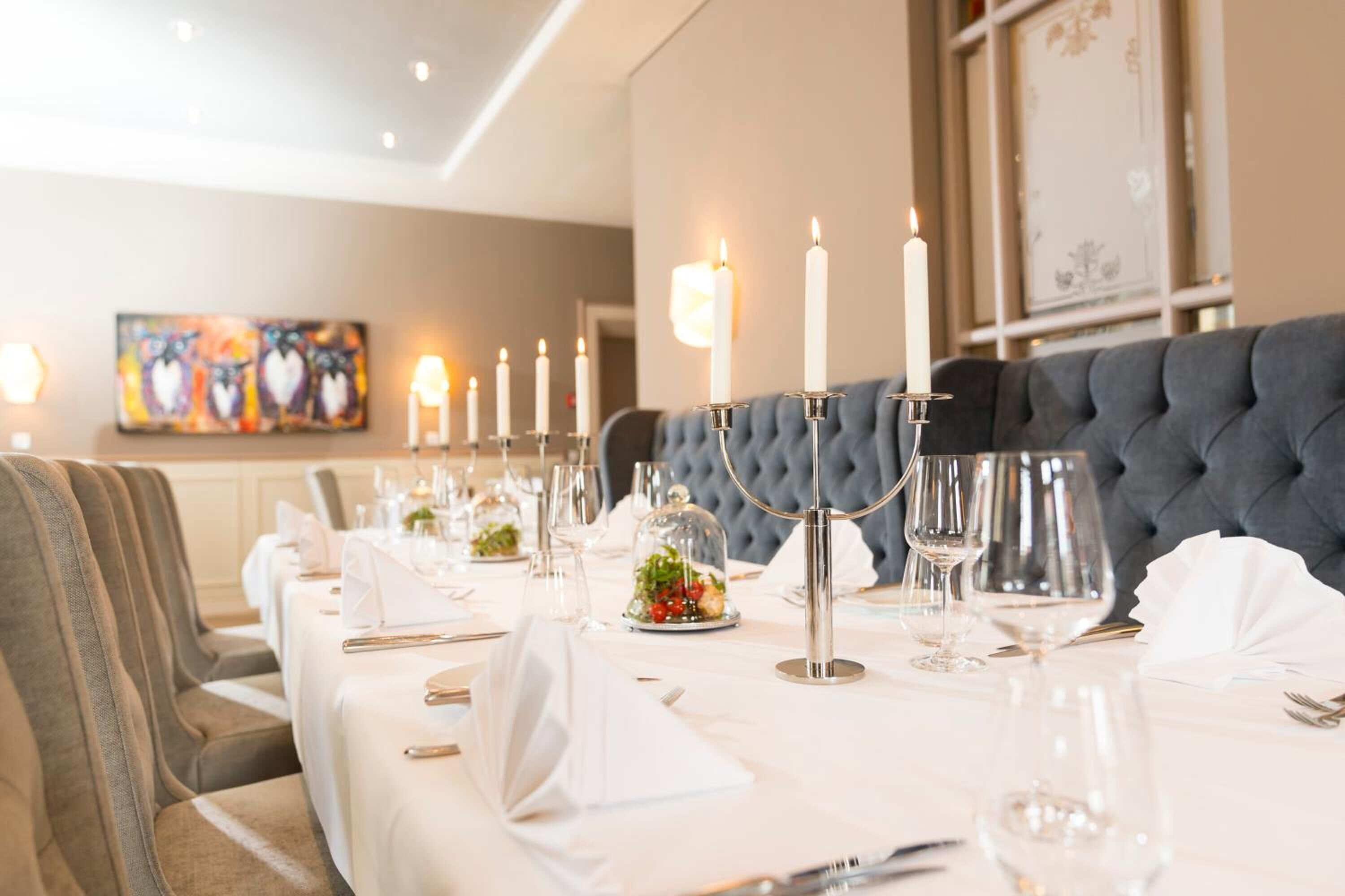 A dining table set with candles, glassware, and a decorative centerpiece.