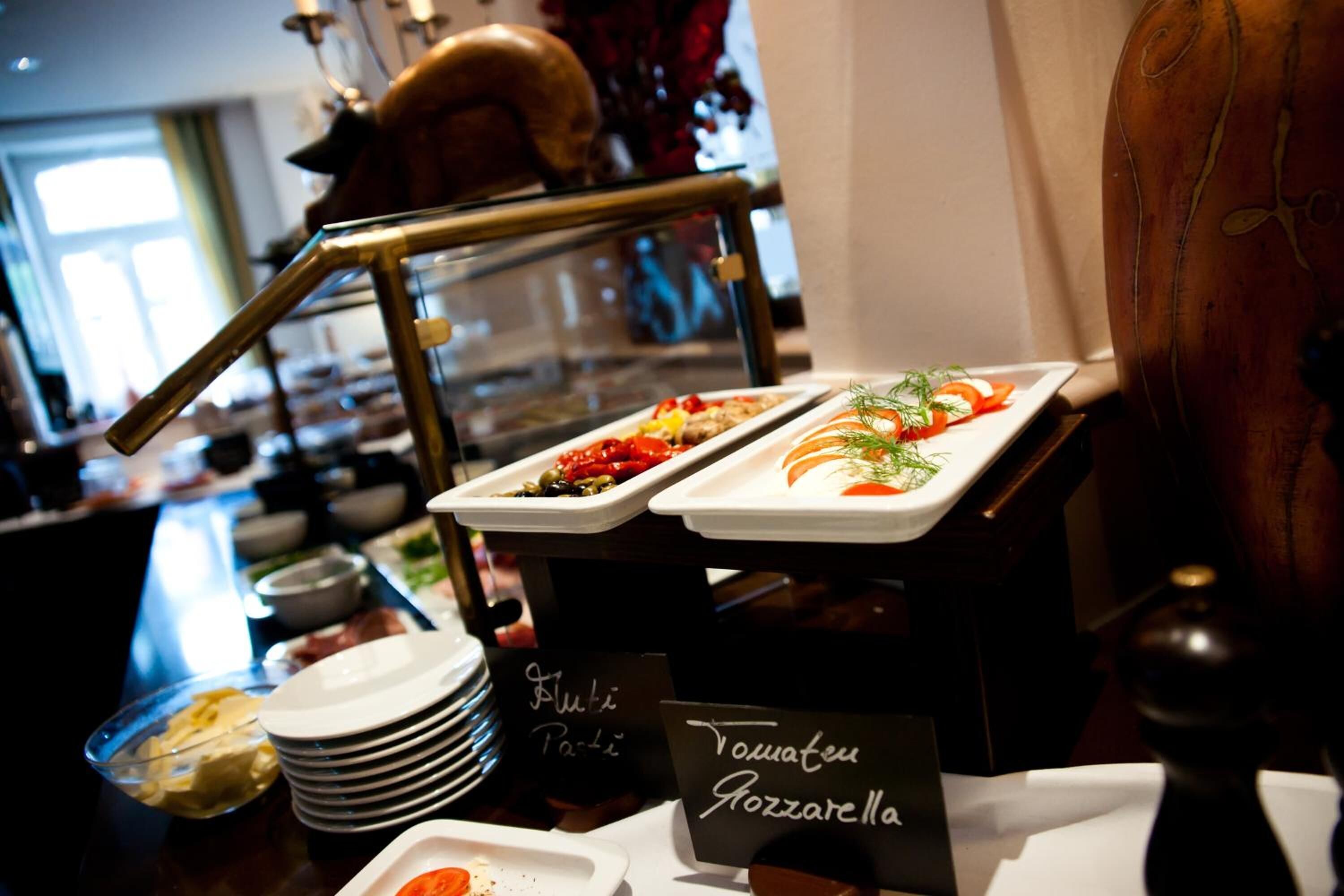 A buffet setup with labeled dishes including 'Tomatee Gazzarella'.