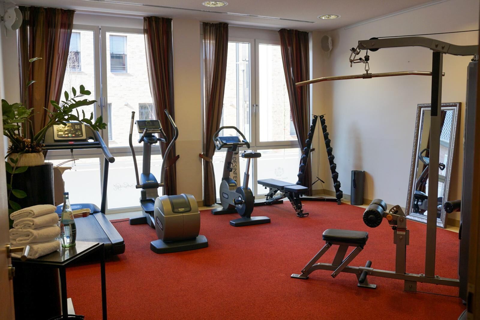 A gym with cardio machines, a bench press, and a mirror.