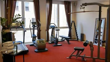 A gym with cardio machines, a bench press, and a mirror.