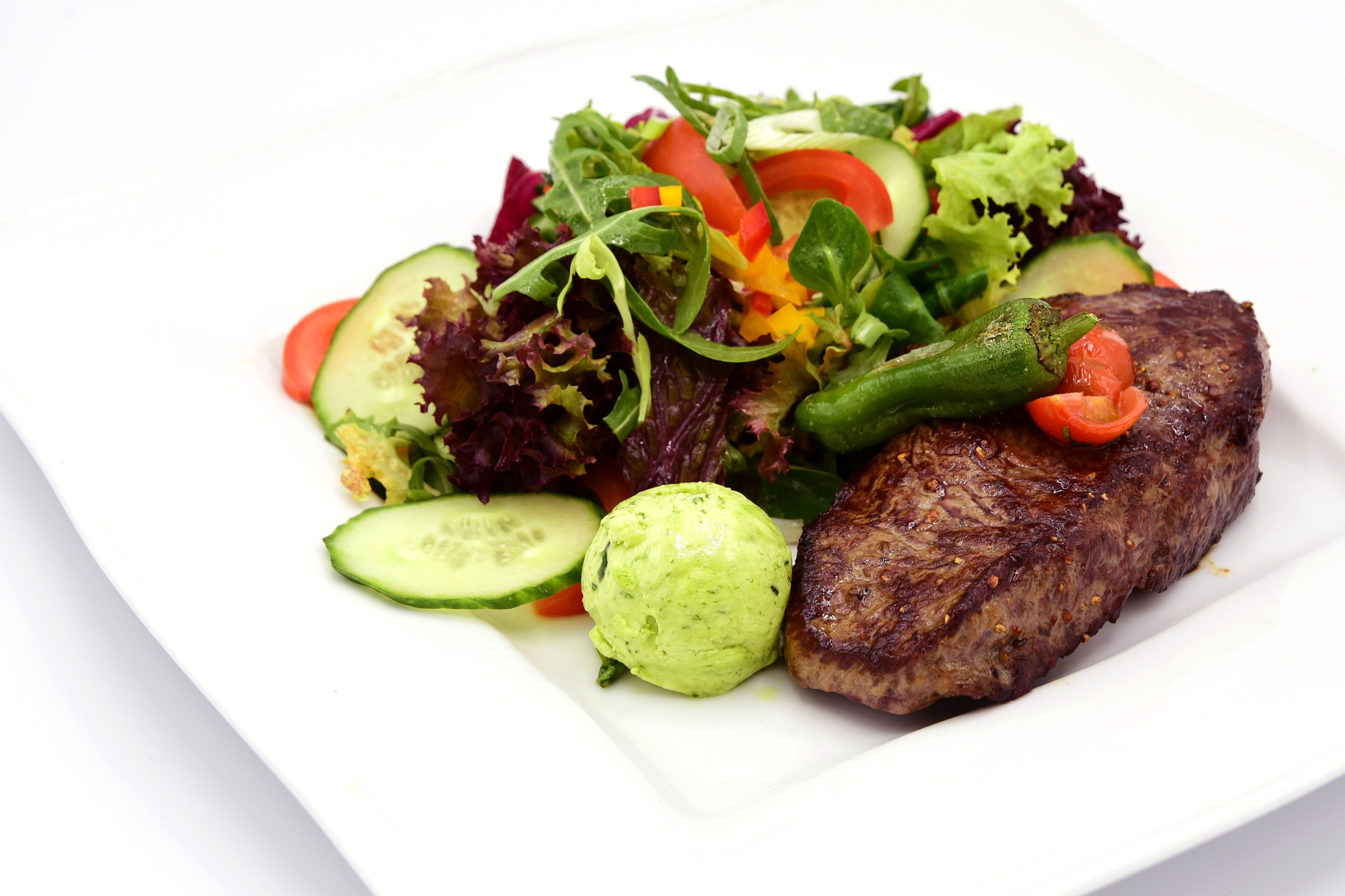 Une assiette avec un steak et une salade composée.