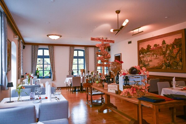 A dining area with tables set for service, a wooden bar with bottles, and a large painting on the wall. - Schaumburger Ritter Hotel & Restaurant (Rinteln)
