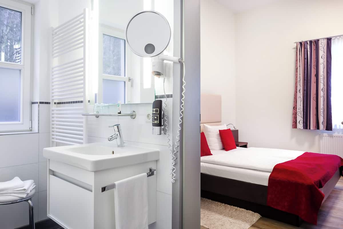 A modern bathroom with a sink, mirror, and towel rack.