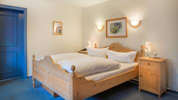 Une chambre à coucher avec un lit en bois, des tables de chevet, une commode et des lampes fixées au mur.