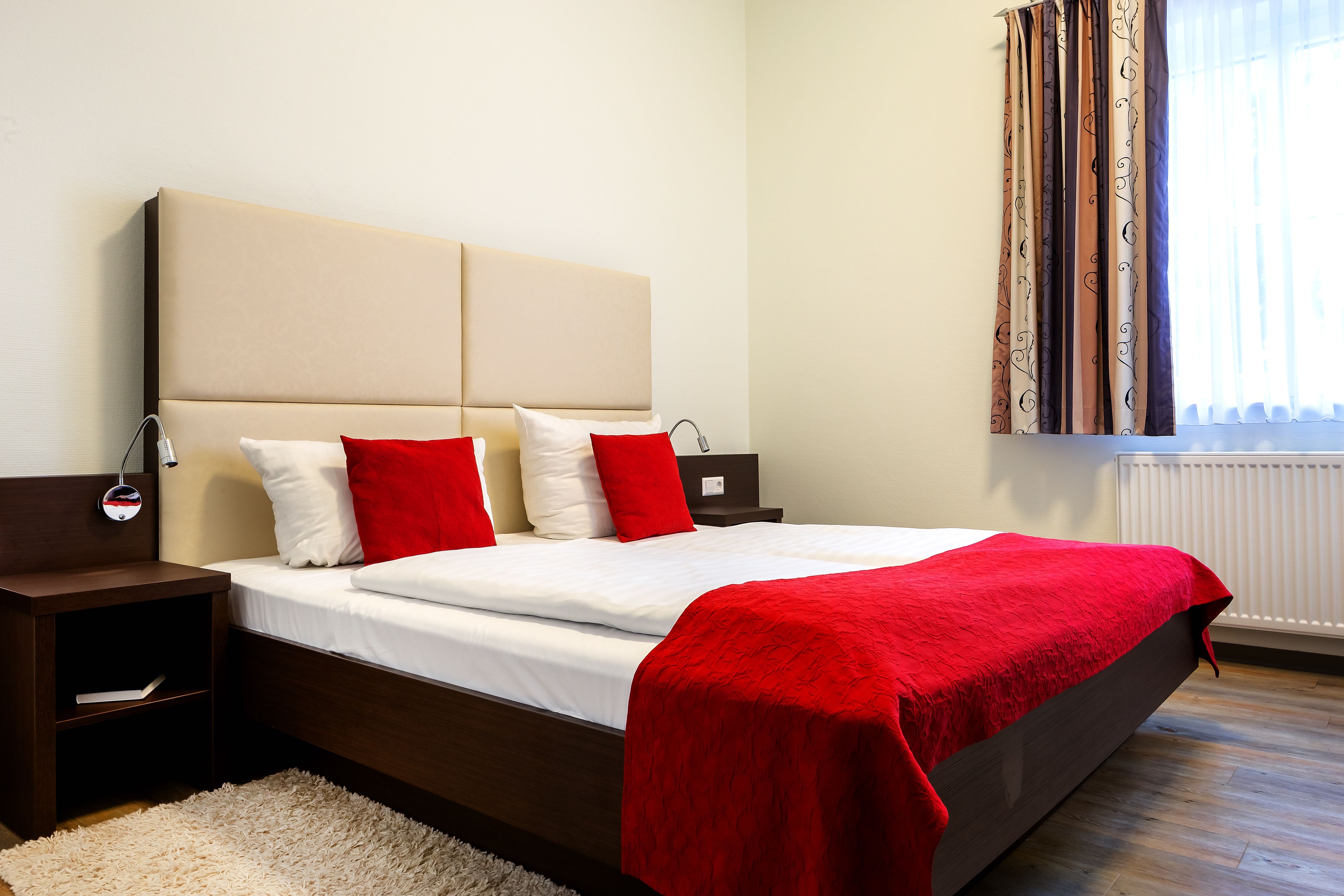 Un dormitorio moderno con una cama grande, una mesita de noche y un ventanal con cortinas.