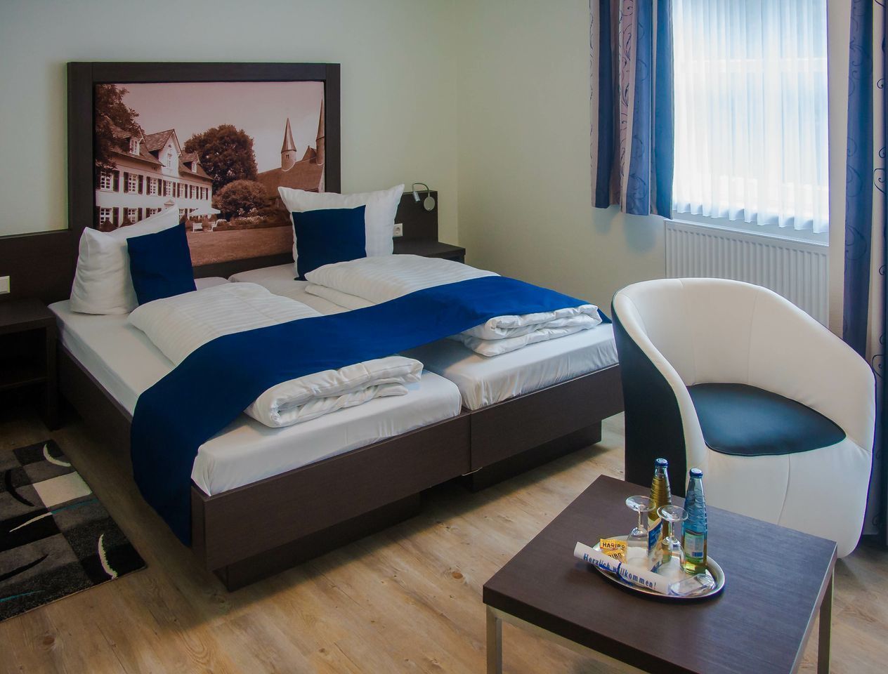 Habitación de hotel con cama, una silla, una mesa con comodidades y una ventana con cortinas.