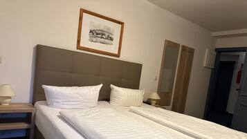A hotel room with a large bed, two bedside tables, a framed picture on the wall, and a door to the right.