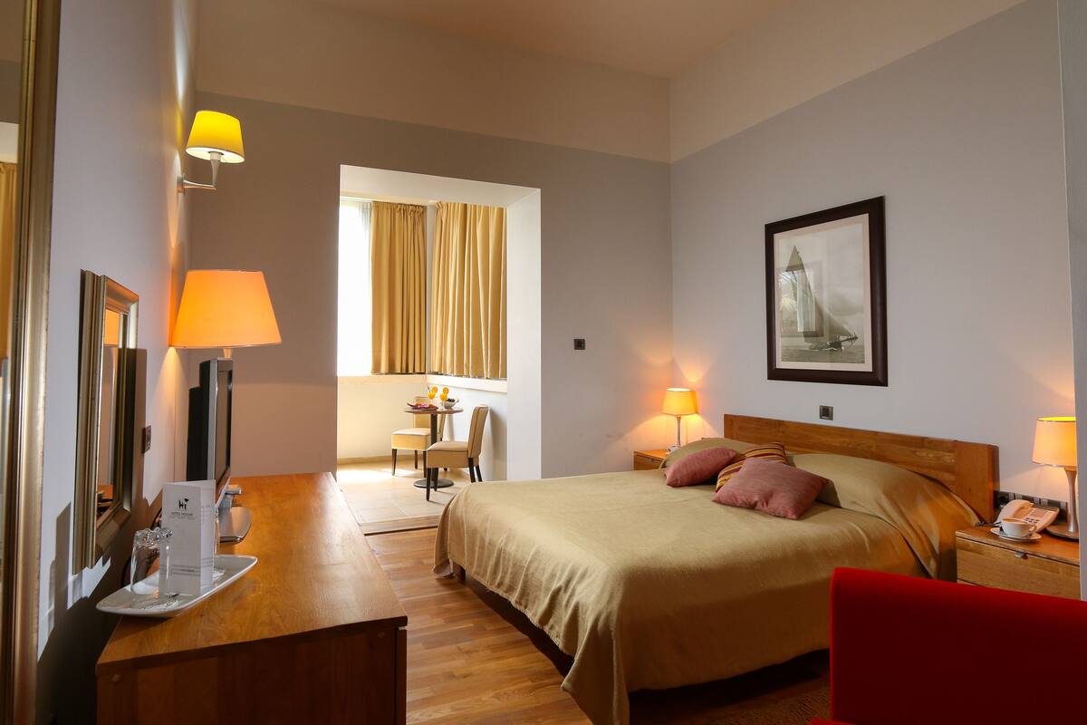 Habitación de hotel con cama, mesita de noche, lámpara y un cuadro en la pared.