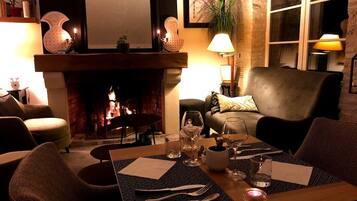 Un comedor acogedor con chimenea, una mesa dispuesta para dos personas y asientos cómodos.