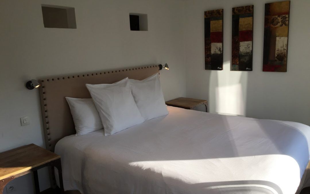 A neatly made bed with a headboard, two bedside tables, and three wall-mounted artworks.