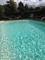 Una piscina cristalina con solárium y sillas de descanso.