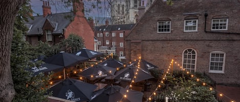 A courtyard with outdoor seating and umbrellas, surrounded by historic buildings.