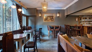A cozy restaurant with wooden furniture, a bar area, and a stone wall. - The Fat Badger (York)