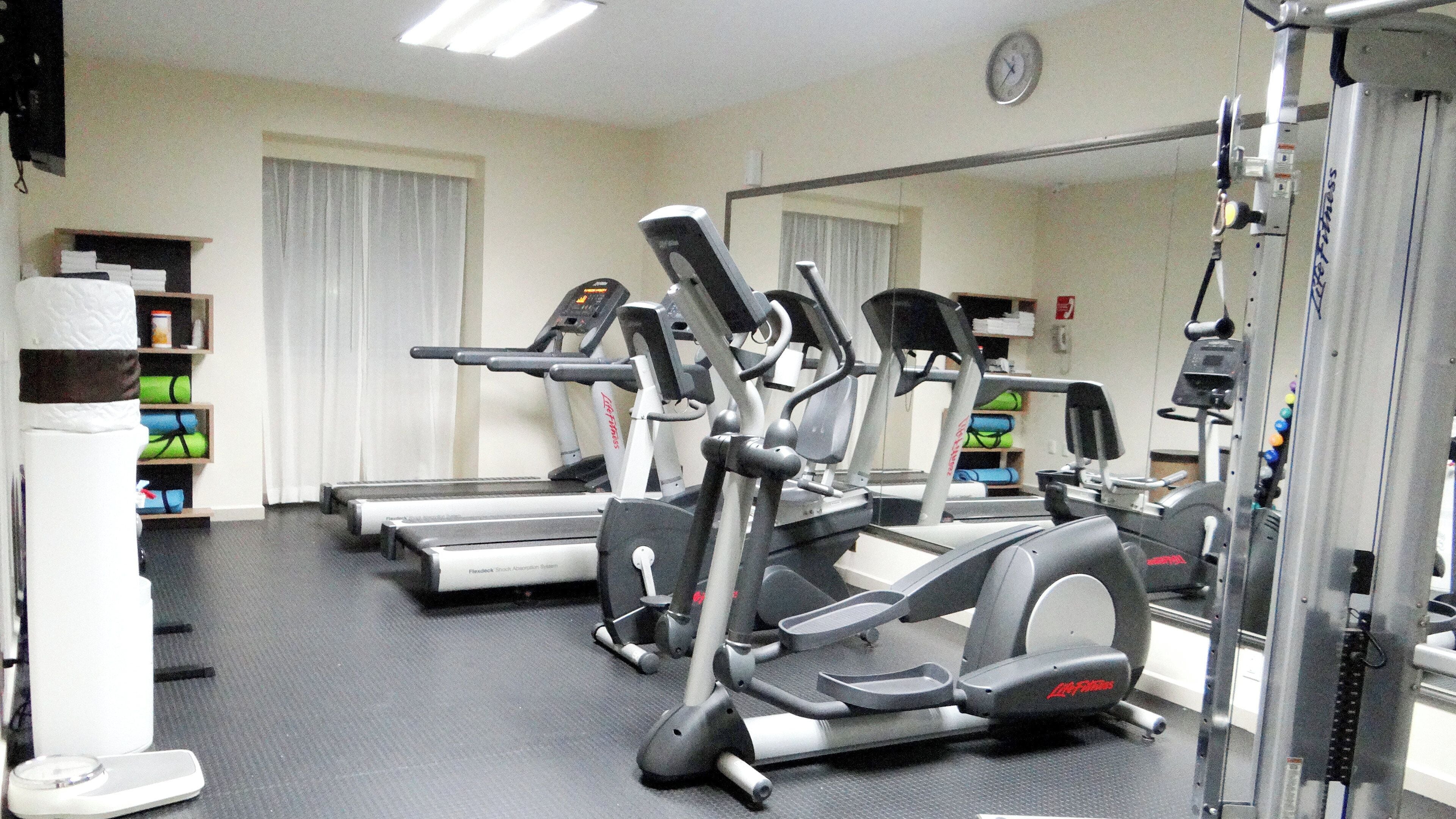 A gym with treadmills, elliptical machines, and weight equipment.