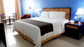 A hotel room with a bed, bedside tables, a chair, and a desk.