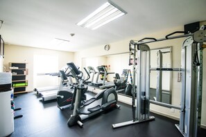 Une salle de sport équipée de tapis de course, de vélos elliptiques et de matériel de musculation.