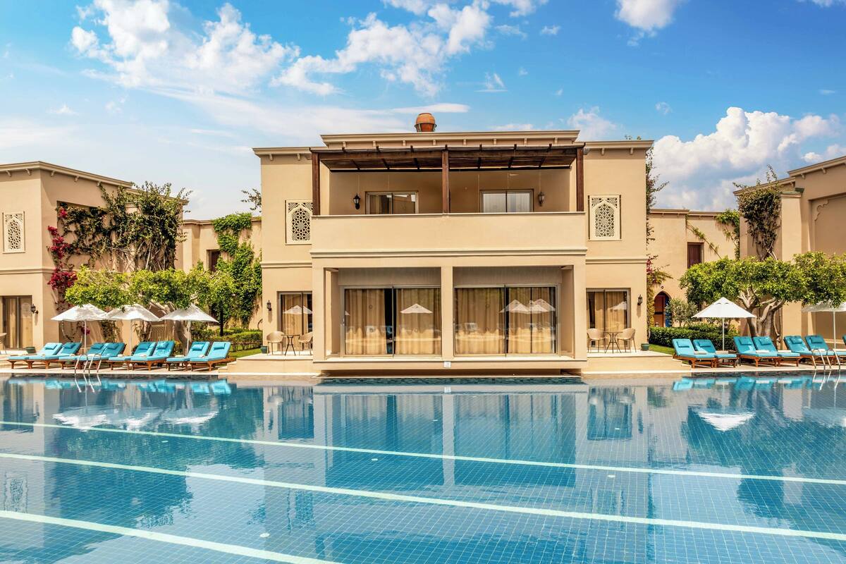 Ein Hotel mit Pool, Liegestühlen und einem zweistöckigen Gebäude mit Balkonen.
