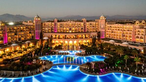A large hotel with multiple balconies, a central courtyard, and a swimming pool.