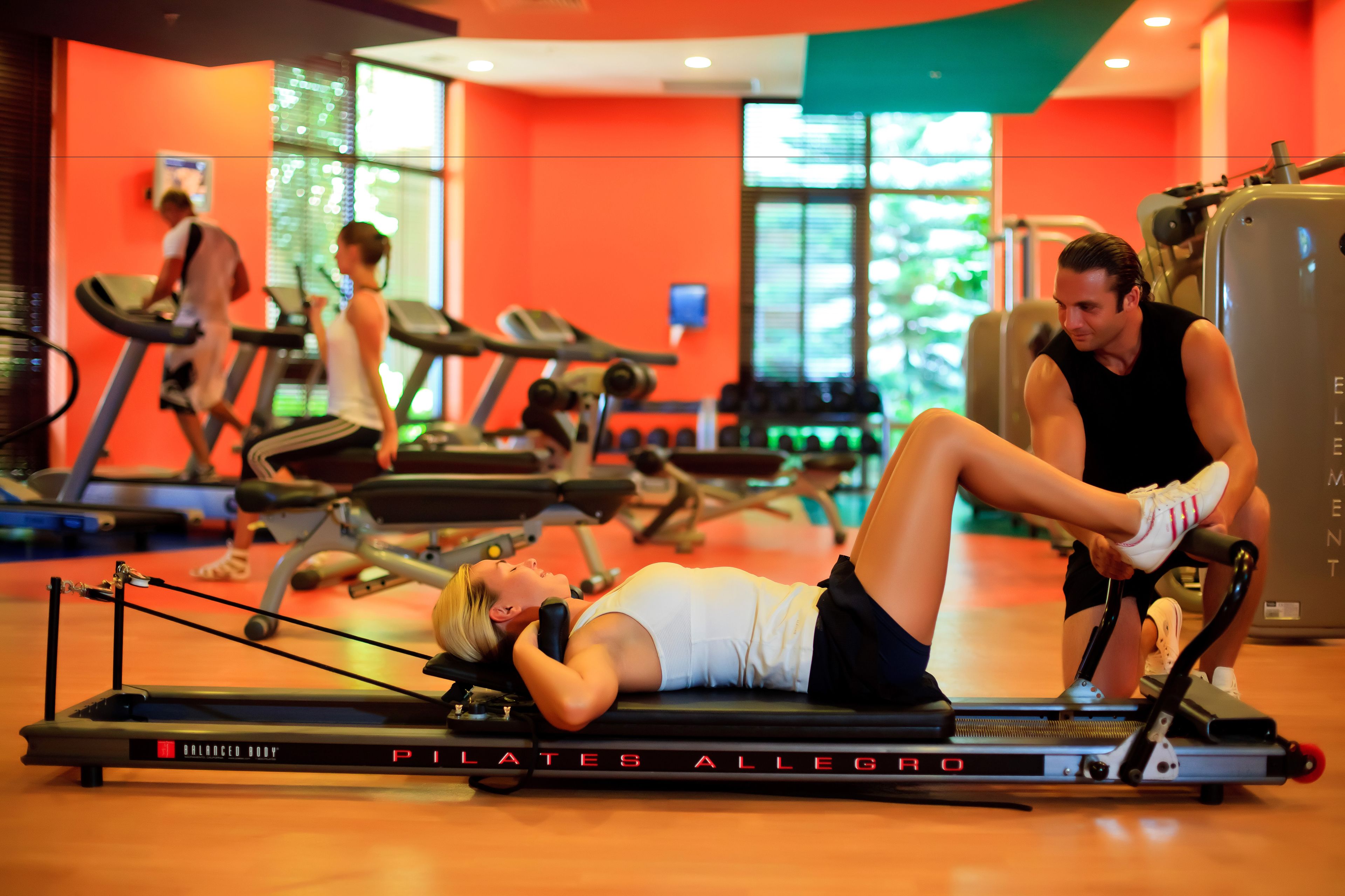 Ein Fitnessraum mit Laufbändern, einem Pilatesgerät und Gewichtstrainern.