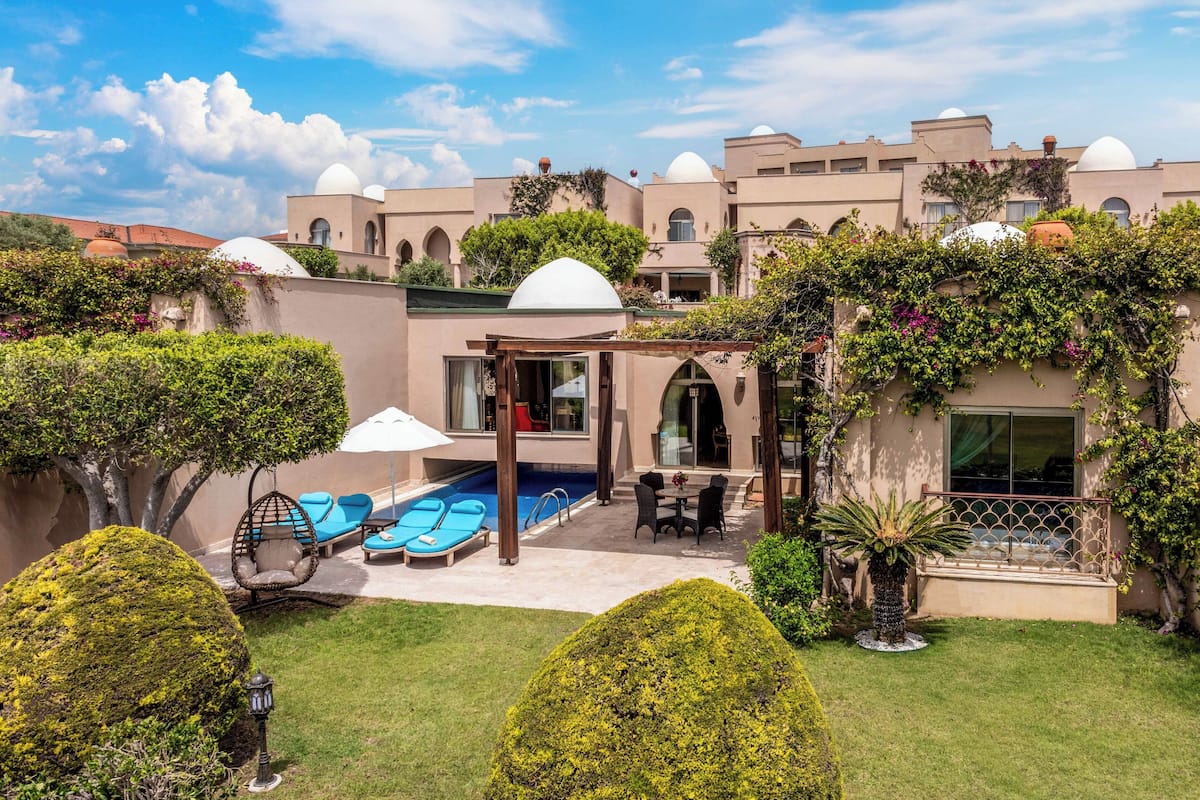 Ein Innenhof mit Swimmingpool, Liegestühlen und einer Pergola.