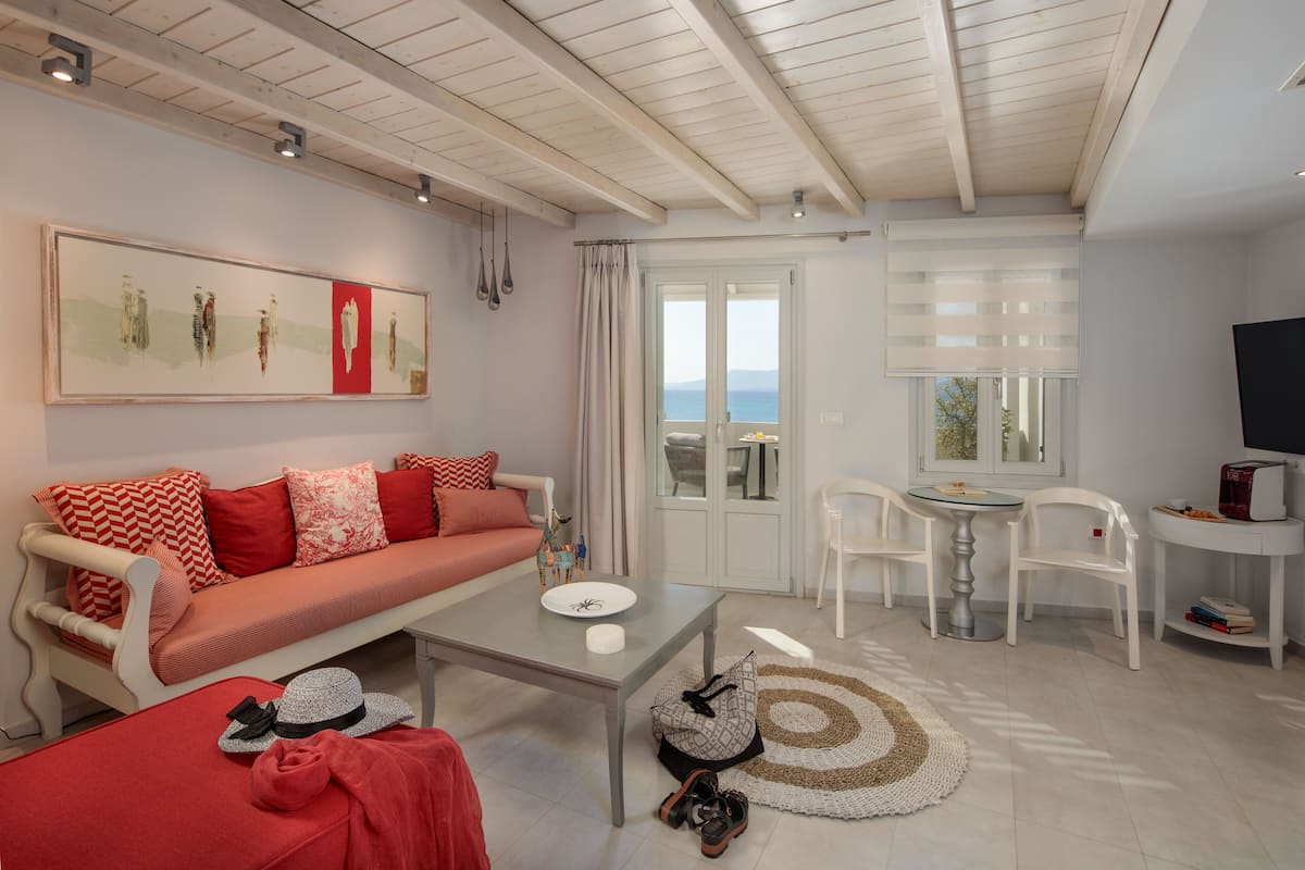 Een moderne woonkamer met een bank, salontafel en uitzicht op zee door de glazen deur.