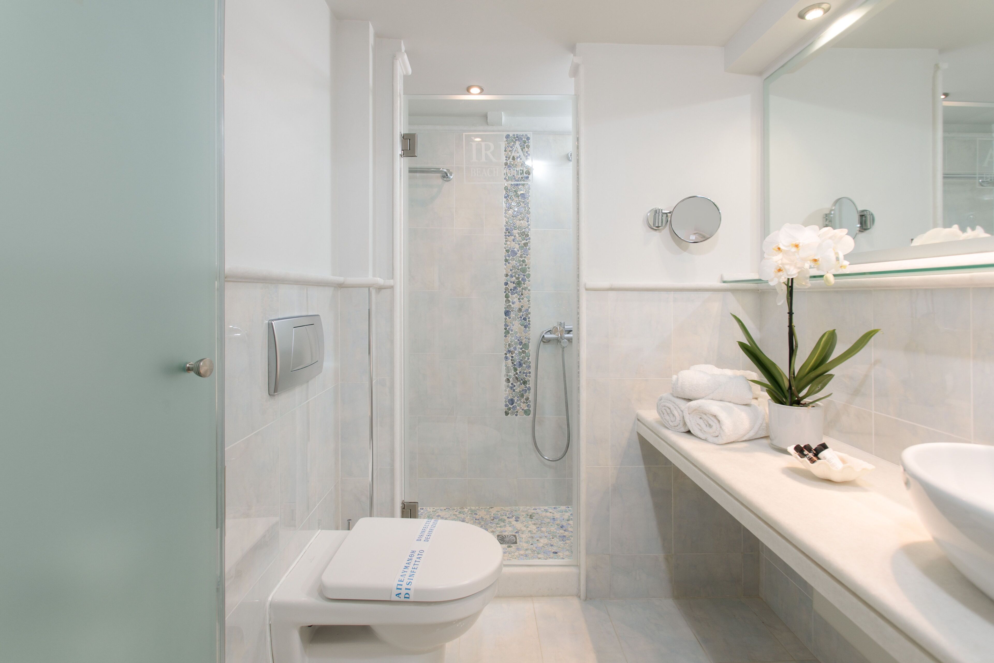 Une salle de bain moderne avec une douche à parois de verre, des toilettes, un lavabo et un miroir.