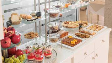 Ein Buffet mit verschiedenen Speisen, darunter Gebäck, Desserts und Früchte.