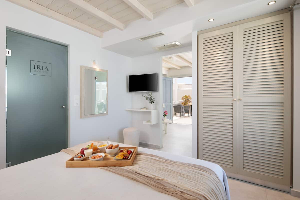Een hotelkamer met een bed, een ontbijttafel, televisie en een kledingkast.