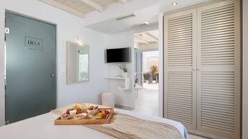Habitación de hotel con cama, bandeja de desayuno, televisor y armario.