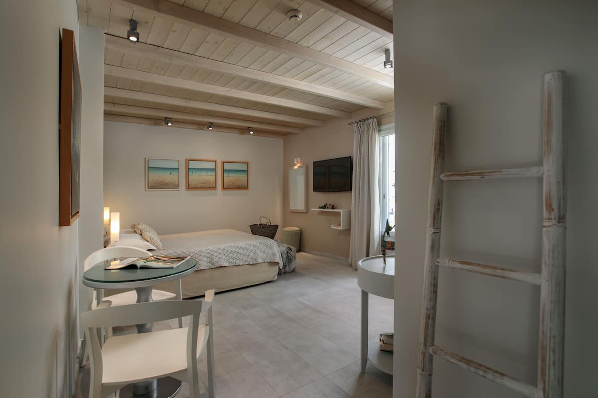 Een slaapkamer met een bed, nachtkastje en een televisie aan de muur.
