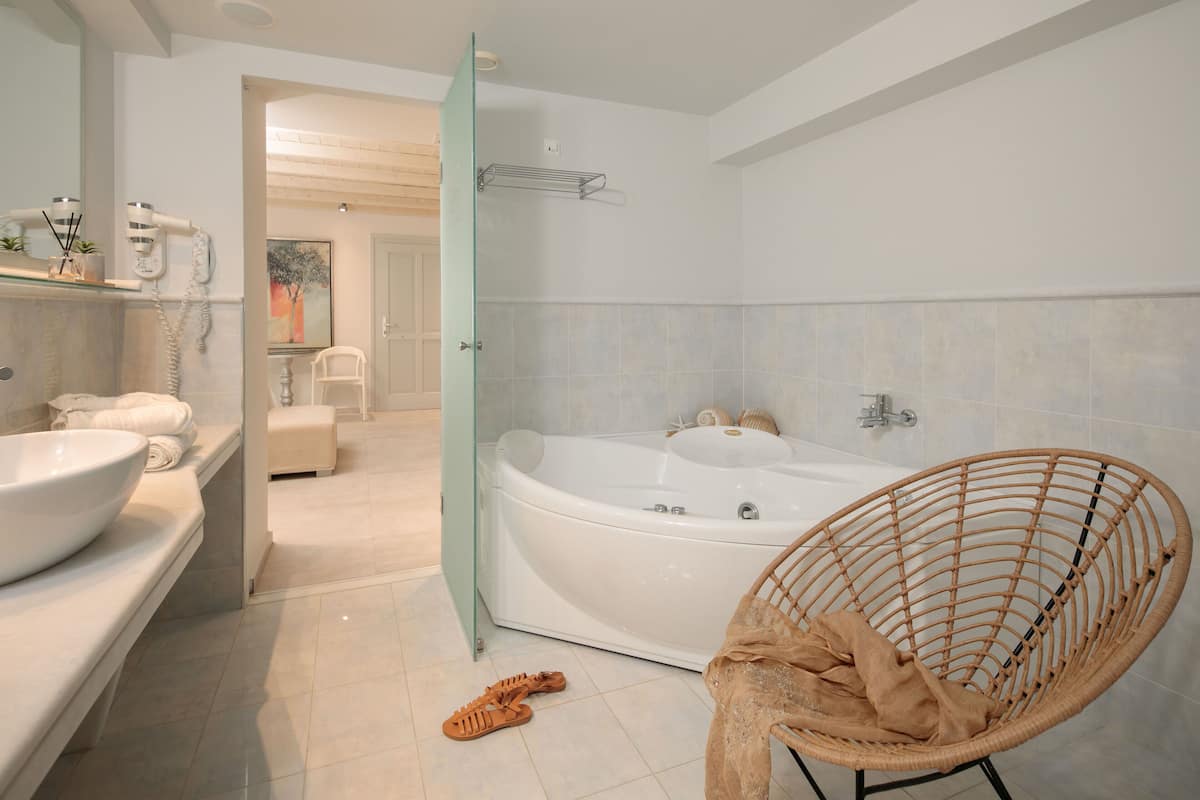 Een moderne badkamer met een groot bad, een rieten stoel en een douchecabine van glas.