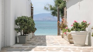 A stone-paved pathway leading to a body of water with potted plants on either side. - Iria Beach art hotel (Naxos)