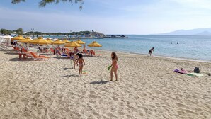 A beach with sun loungers and umbrellas, a clear sky, and a calm sea. - Iria Beach art hotel (Naxos)