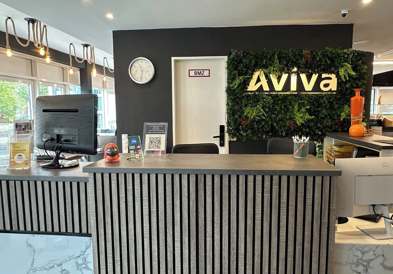 Un comptoir d’accueil avec une horloge numérique, une enseigne indiquant « Aviva » et un code QR.