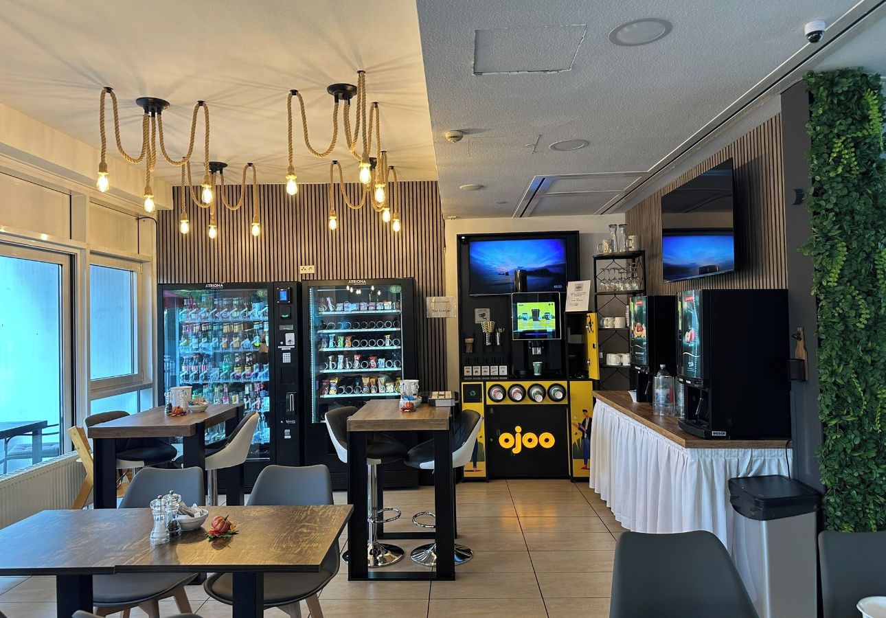 Un restaurant amb màquina expenedora, pantalla de televisió i zona de bar.