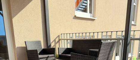 An outdoor seating area with wicker furniture and a metal railing.
