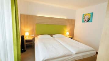 Ein Hotelzimmer mit Bett, Nachttischlampen, einem grünen Vorhang und einem Wandbild.