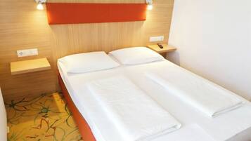 A single bed with white linens, a wooden headboard, and bedside tables with lamps.