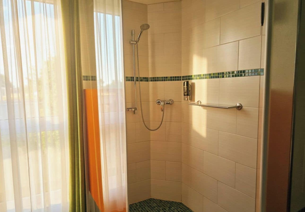 Una dutxa amb porta de vidre, vàrters de mà i accessori de dutxa manual.
