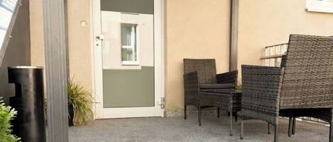 An outdoor seating area with wicker chairs and a door.