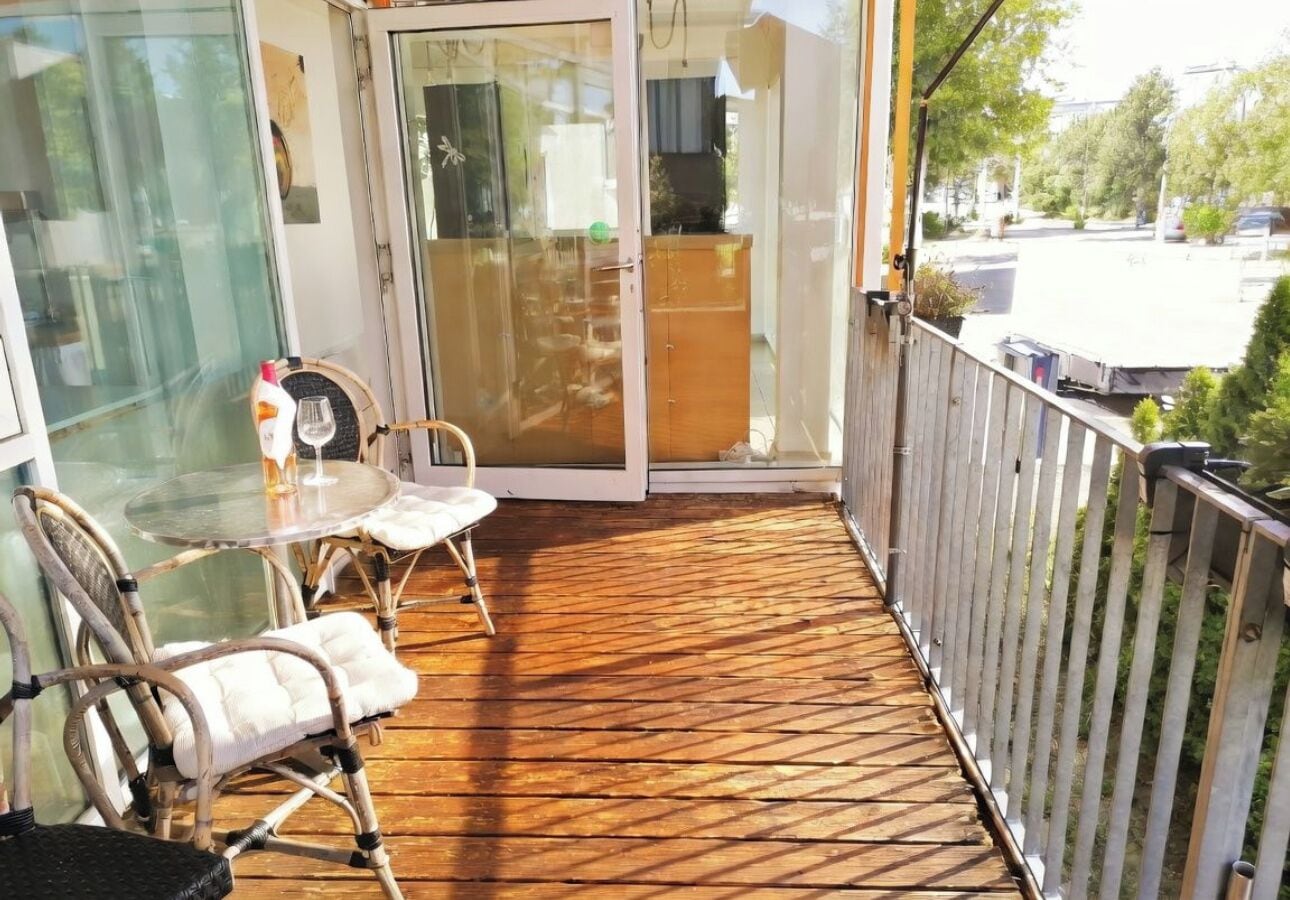 A balcony with a wooden floor, glass doors, and wicker chairs.