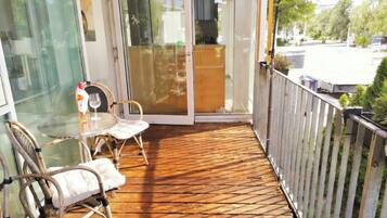 A balcony with a wooden floor, glass doors, and wicker chairs.