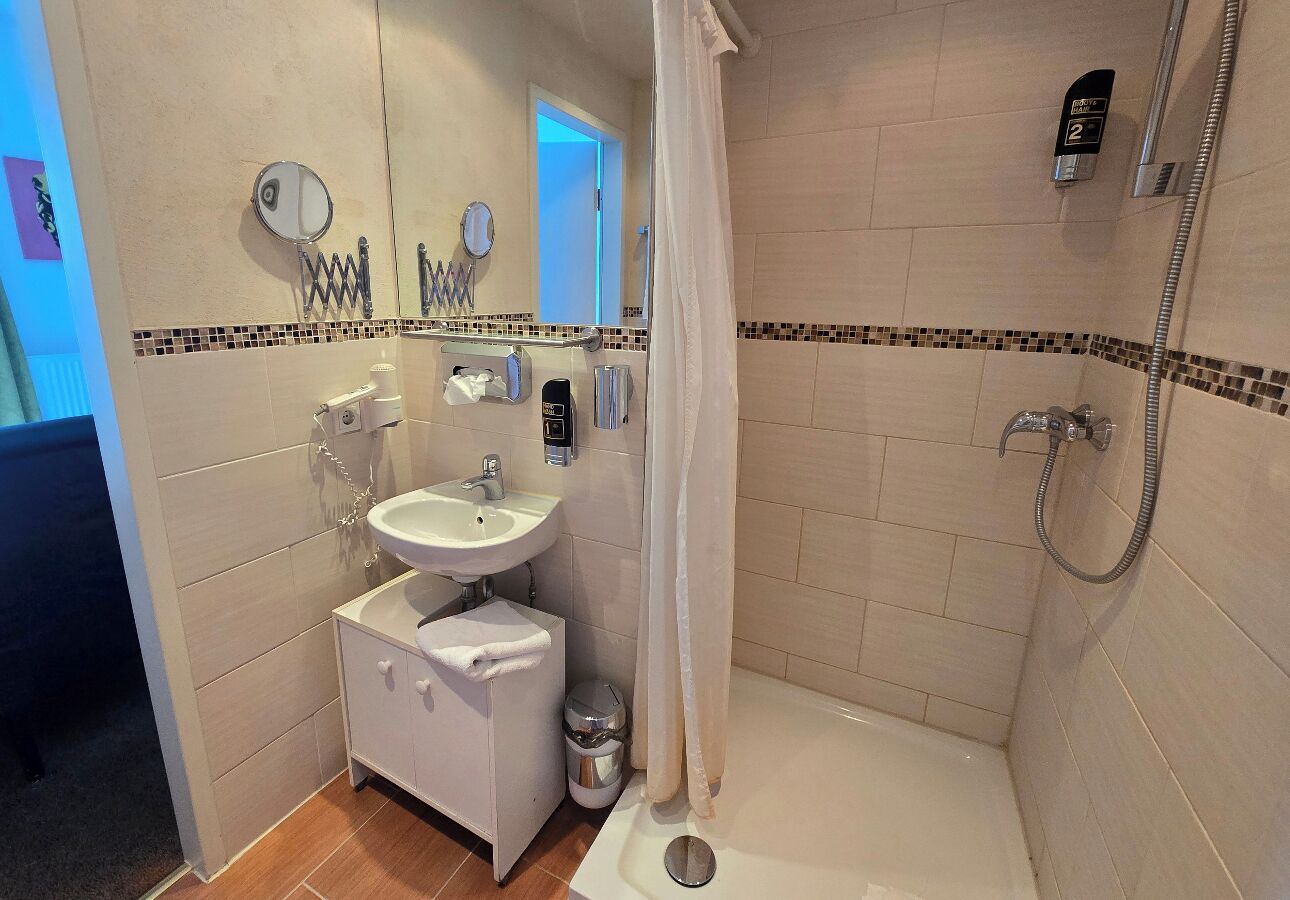 A bathroom with a shower, a sink, and a mirror.