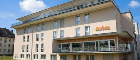 A multi-story building with a flat facade, a balcony on the upper floor, and a sign that reads 'Aviva.'