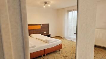 A hotel room with a bed, a nightstand, a wooden headboard, and a window with curtains.