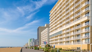 Un hôtel situé en bord de mer, doté de nombreux balcons, d’une promenade en bord de plage et offrant une vue sur un ciel dégagé.