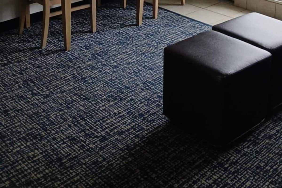 Een hotelkamer met een houten tafel, twee stoelen, een aan de muur bevestigde televisie, een deur en een raam.